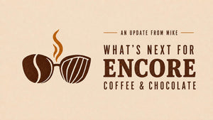 An Update from Mike: What’s Next for Encore Coffee & Chocolate, with coffee bean and cacao pod glasses and rising steam.