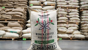 Bag of Colombian coffee with backdrop of pallets of Colombian coffee