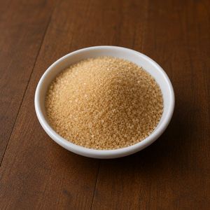 Organic cane sugar in a small white ceramic dish on a warm wooden tabletop.