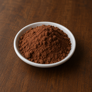 Premium cocoa powder in a small white ceramic dish on a warm wooden tabletop.