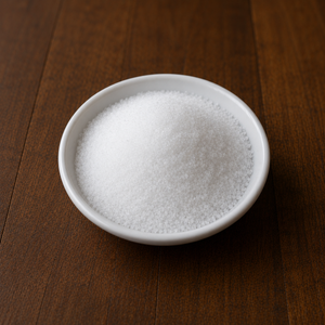 Fine sea salt in a small white ceramic dish on a warm wooden tabletop.