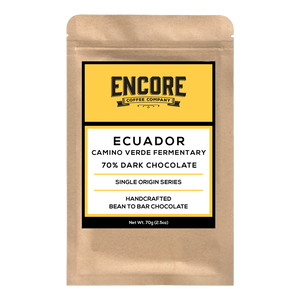 A rectangular dark chocolate bar is shown with the brand name "Encore" written in white letters on the top left corner of the packaging. The background of the packaging is a light brown color and features a white square in the center with the word "Ecuador" written in white letters. The chocolate bar is surrounded by images of cocoa pods and leaves, also in white.