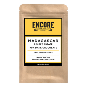 Image of Encore Coffee's 70% Dark Madagascar chocolate bar. The chocolate is shown unwrapped with the bar's texture visible. The packaging is visible in the background with the Encore Coffee logo prominently displayed.